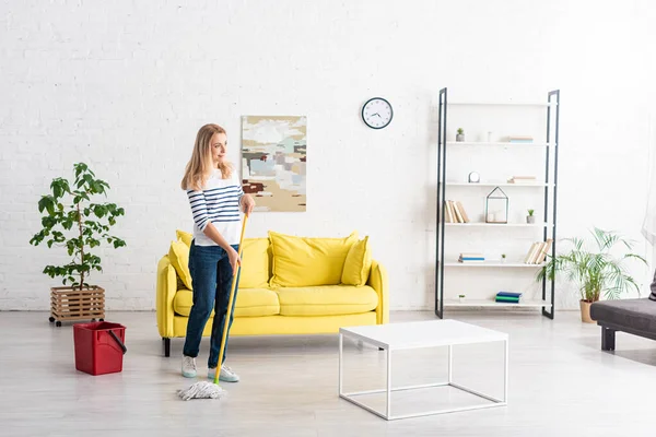 Mulher loira limpando com esfregona na sala de estar — Fotografia de Stock