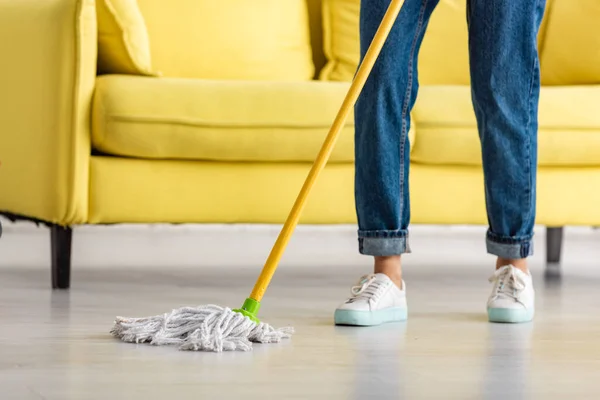 Vista ritagliata della donna che pulisce il pavimento con lo straccio in soggiorno — Foto stock