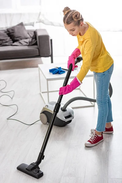 Child cleaning up with vacuum cleaner in living room — Stock Photo