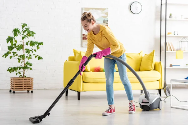 Kind lächelt und räumt mit Staubsauger im Wohnzimmer auf — Stockfoto