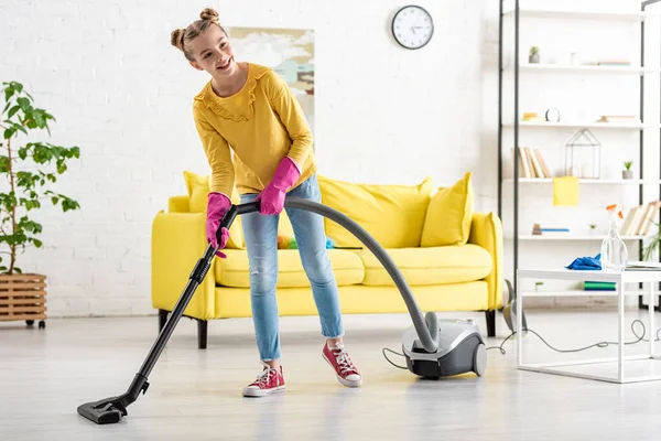 Niedliches Kind lächelt und räumt mit Staubsauger im Wohnzimmer auf — Stockfoto