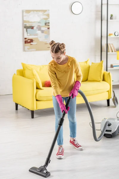 Cute kid cleaning up with vacuum cleaner in living room — Stock Photo