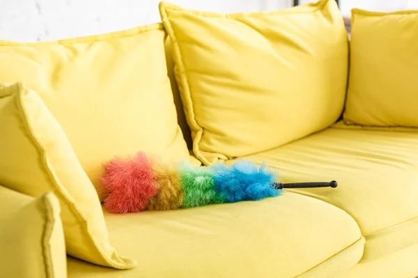 Gelbes Sofa mit buntem Staubwedel im Wohnzimmer — Stockfoto