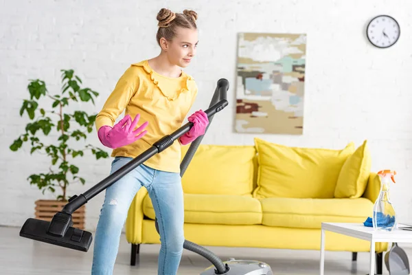 Child imitating playing guitar with vacuum cleaner in living room — Stock Photo