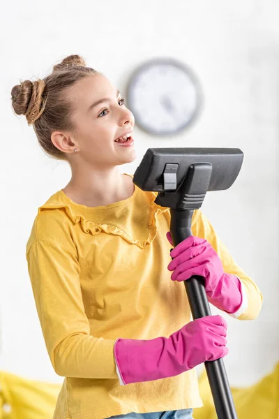 Niedliches Kind singt mit Staubsauger und lächelt im Wohnzimmer — Stockfoto