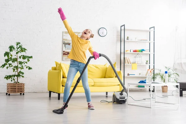 Kind mit geschlossenen Augen und ausgestreckter Hand singt mit Staubsauger im Wohnzimmer — Stockfoto