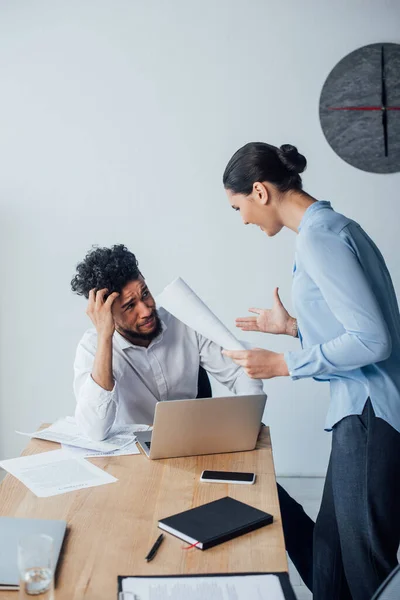 Selective focus of cheerful mexican businesswoman holding documents and looking at confused african american man in office — Stock Photo