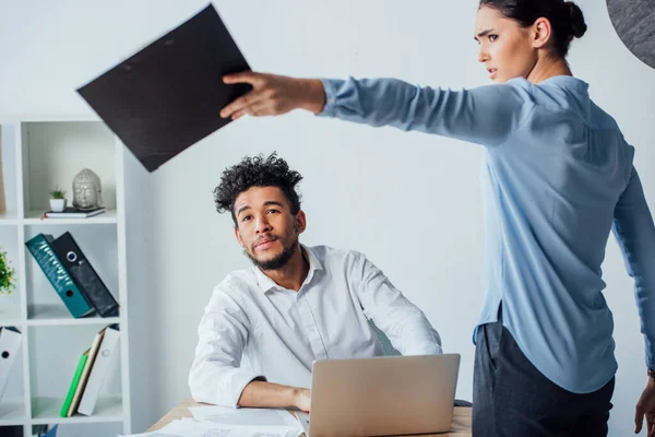 Focus selettivo della donna d'affari messicana che tiene appunti vicino all'uomo d'affari afroamericano al tavolo in ufficio — Foto stock