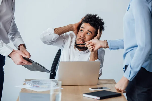 Selective focus of business people standing near scared african american businessman in office — Stock Photo