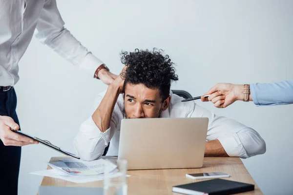 Selective focus of business people holding clipboard and pen near confused african american businessman in office — Stock Photo