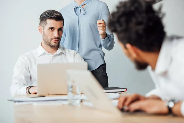 Selective focus of businessman looking at african american colleague at table in office — Stock Photo