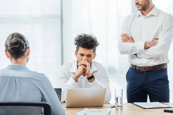 Selektiver Fokus eines nachdenklichen afrikanisch-amerikanischen Geschäftsmannes, der neben Kollegen im Büro sitzt — Stockfoto