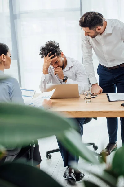 Selective focus of businessman looking at offended african american colleague in office — Stock Photo