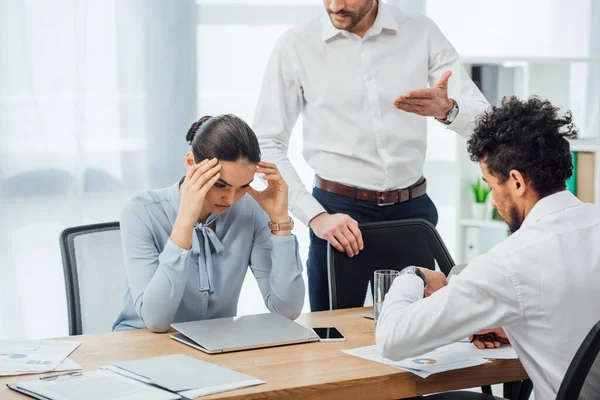 Concentration sélective de l'homme d'affaires pointant avec la main près de collègue mexicain à la table dans le bureau — Photo de stock