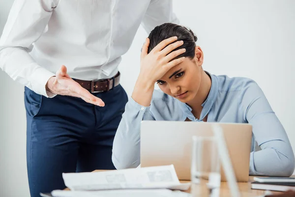 Selektiver Fokus eines Geschäftsmannes, der mit der Hand auf einen traurigen mexikanischen Kollegen zeigt, dessen Hand in der Nähe seines Büroleiters liegt — Stock Photo