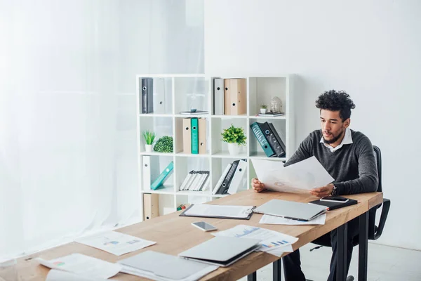 Foco seletivo do empresário afro-americano trabalhando com papéis à mesa no escritório — Fotografia de Stock