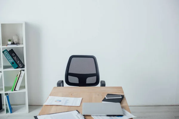 Foco seletivo de smartphone, laptop e papéis na mesa de madeira no escritório — Fotografia de Stock