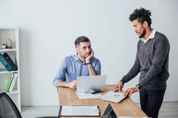 Afrikanischer Geschäftsmann hält Dokument neben Kollegin am Tisch im Büro — Stockfoto