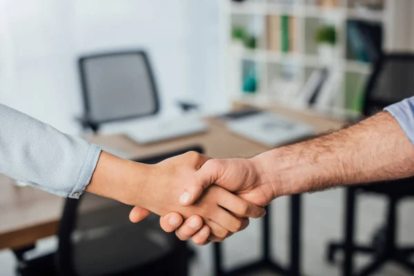 Vista recortada de gente de negocios multicultural estrechando la mano en la oficina - foto de stock