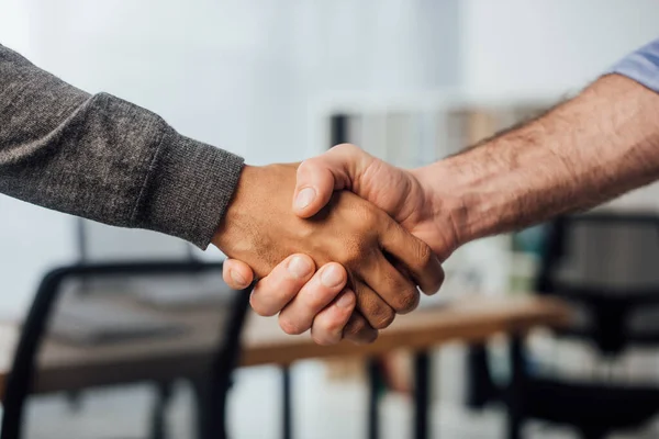 Vista recortada del hombre de negocios afroamericano estrechando la mano con su colega en el cargo - foto de stock