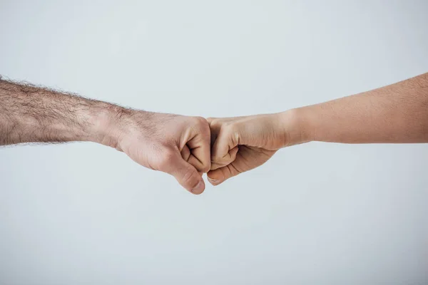 Vista recortada de hombres haciendo gesto de golpe de puño aislado en gris - foto de stock