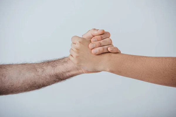 Vista recortada de dos hombres tomados de la mano aislados en gris - foto de stock