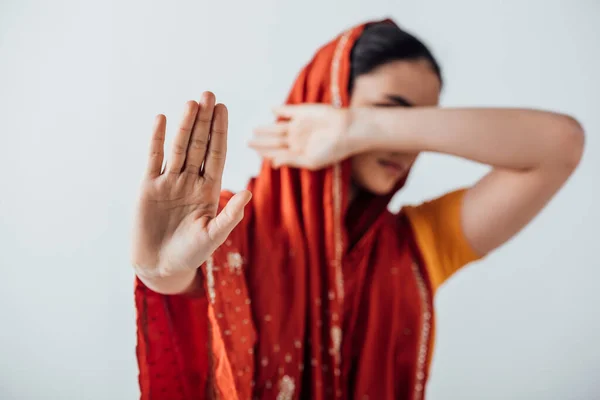 Selective focus of woman in sari showing stop sign and covering face isolated on grey — Stock Photo