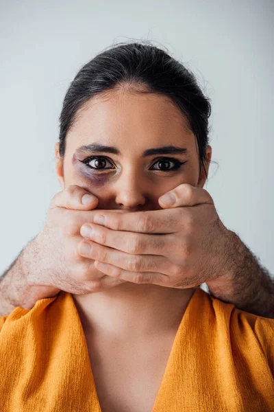 Manos masculinas que cubren la boca a la mujer india con moretones aislados en gris - foto de stock