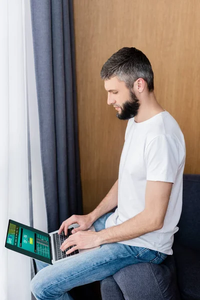 Side view of man using laptop with sports bet website on couch — Stock Photo