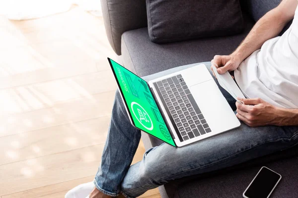 Vista cortada do homem segurando máscara médica perto do laptop com site de compras on-line na tela — Fotografia de Stock