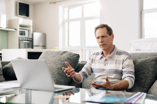 Selective focus of man gesturing near laptop while having video call — Stock Photo