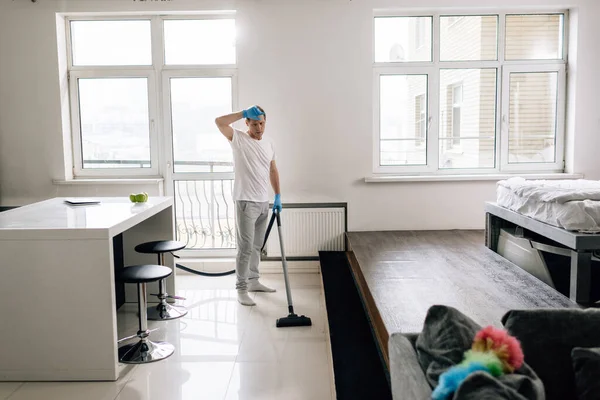 Foco seletivo do homem cansado apartamento de limpeza com aspirador — Fotografia de Stock
