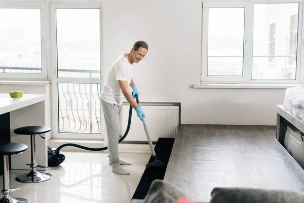 Вибірковий фокус щасливого чоловіка прибирання квартири з пилососом — стокове фото