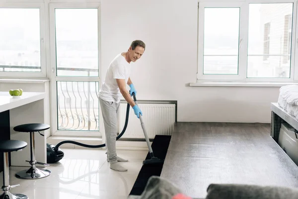 Enfoque selectivo de hombre feliz apartamento de limpieza con aspiradora - foto de stock