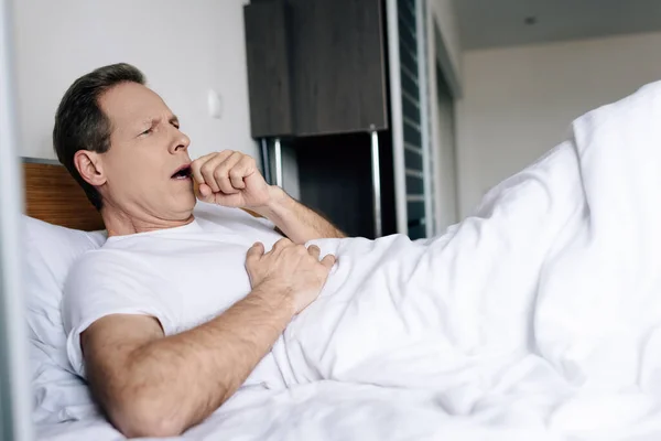Homme malade tousse alors qu'il est allongé sur le lit à la maison — Photo de stock
