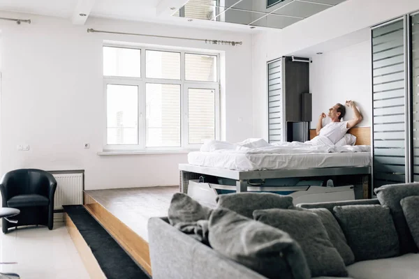 Foco seletivo do homem feliz alongamento no quarto moderno — Fotografia de Stock