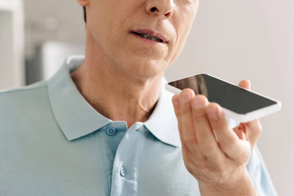 Vista cortada de homem gravando mensagem de voz enquanto segurando smartphone com tela em branco — Fotografia de Stock