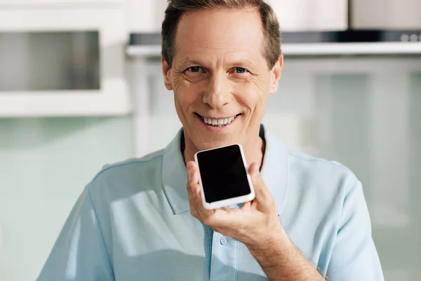 Happy man holding smartphone with blank screen while recording voice message — Stock Photo