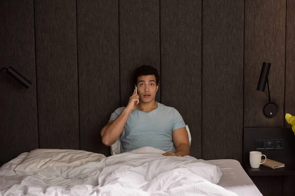 Schöner verwunderter Mischlingshund, der in Quarantäne auf dem Smartphone im Bett spricht — Stock Photo
