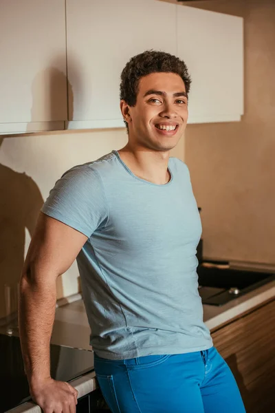 Счастливый мужчина смешанной расы, стоящий на кухне во время самоизоляции — стоковое фото