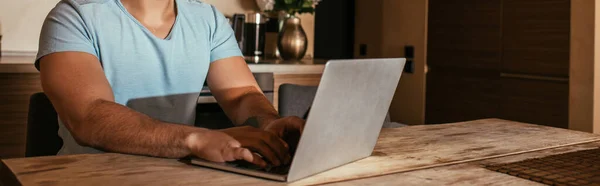 Ausgeschnittene Ansicht eines männlichen Mischlings, der mit Laptop in der Küche arbeitet, während er sich selbst isoliert, Website-Header — Stockfoto