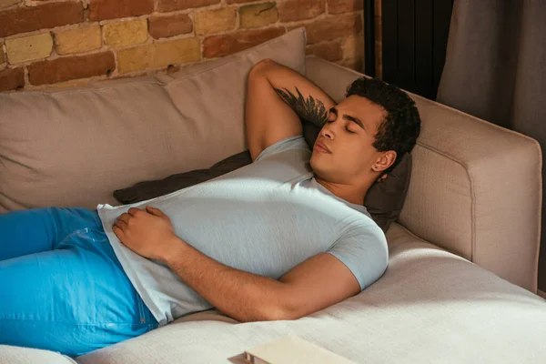 Schöner Mischlingsmann schläft während der Quarantäne zu Hause auf dem Sofa — Stockfoto