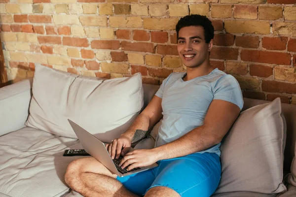 Усміхнений дворасовий чоловік охолоджує ноутбук на дивані на карантині — стокове фото