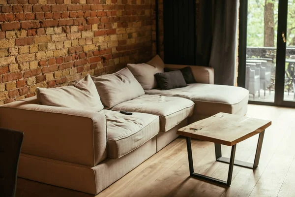 Intérieur moderne du salon avec canapé beige, table et télécommande — Photo de stock