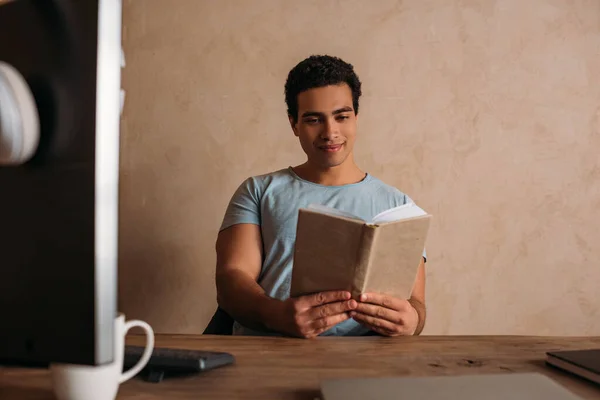 Feliz carrera mixta freelancer lectura libro en casa oficina durante cuarentena - foto de stock