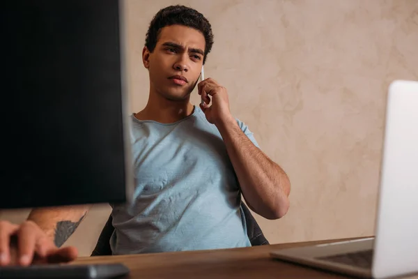 Worried mixed race freelancer working with laptop and computer in home office during quarantine — Stock Photo