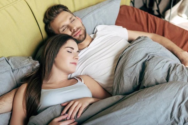 Счастливый мужчина и привлекательная женщина, спящая в постели — стоковое фото