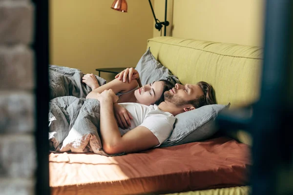 Selective focus of handsome man and attractive woman sleeping in bed — Stock Photo