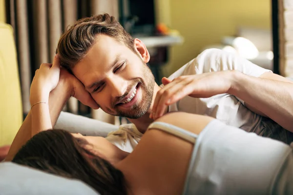 Selective focus of cheerful bearded man looking at girlfriend in bed — Stock Photo