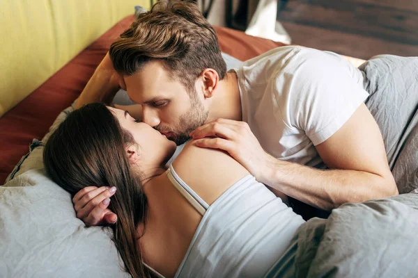 Hombre guapo y atractiva mujer besándose en la cama - foto de stock